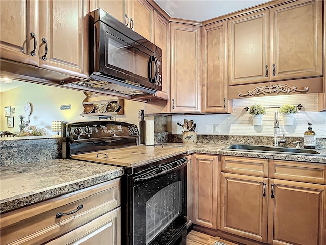 kitchen featuring black appliances, wood-type flooring, and sink