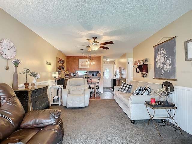 living room featuring ceiling fan with notable chandelier, hardwood / wood-style floors, and a textured ceiling