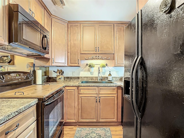 kitchen with sink, black appliances, and light hardwood / wood-style floors