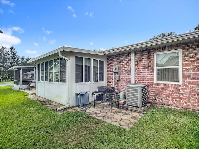 rear view of property with a patio, a lawn, cooling unit, and a sunroom