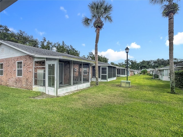 rear view of property with a lawn and a sunroom