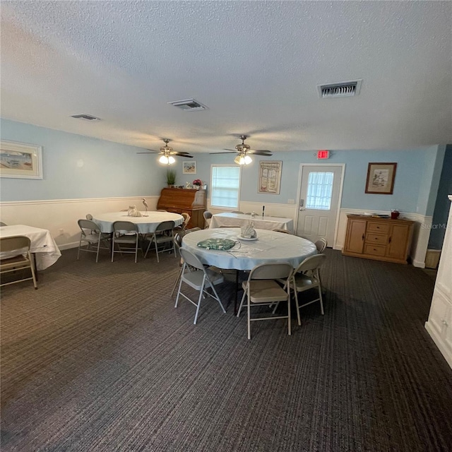 carpeted dining space with a textured ceiling and ceiling fan