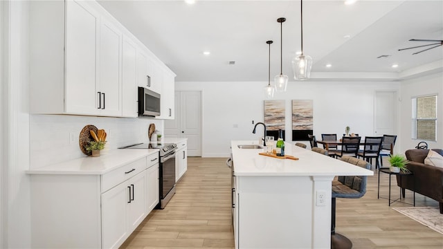 kitchen featuring pendant lighting, a breakfast bar, light wood-type flooring, an island with sink, and stainless steel appliances