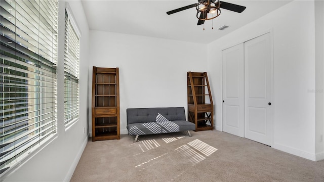 living area with ceiling fan and light colored carpet