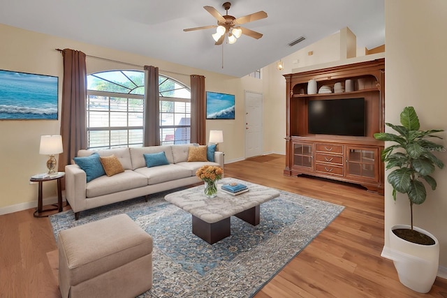 living room with ceiling fan, light wood-type flooring, and vaulted ceiling