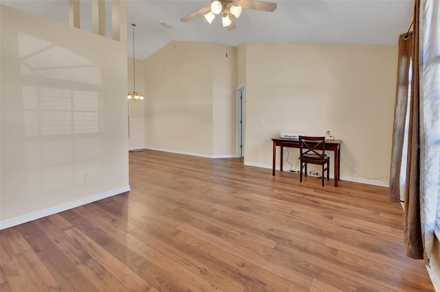 empty room with ceiling fan with notable chandelier, wood-type flooring, and lofted ceiling