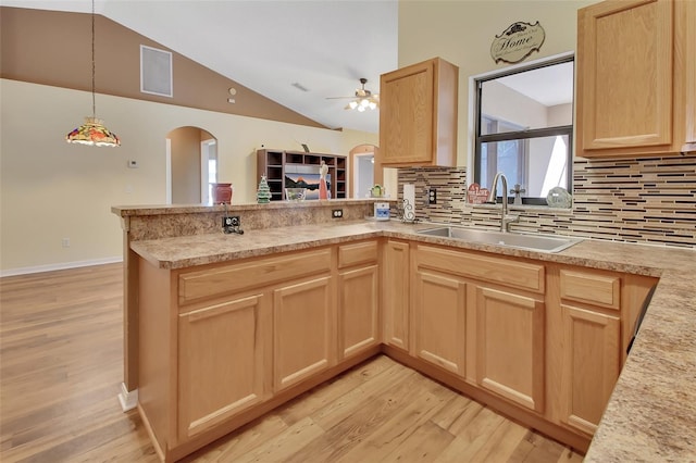 kitchen featuring sink, light brown cabinetry, tasteful backsplash, light hardwood / wood-style floors, and kitchen peninsula