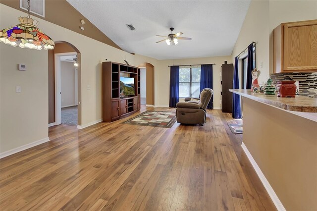 living room with ceiling fan, lofted ceiling, and light wood-type flooring