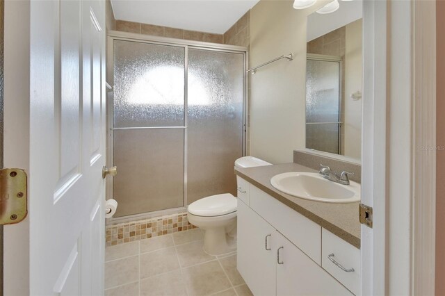 bathroom featuring tile patterned flooring, vanity, toilet, and walk in shower