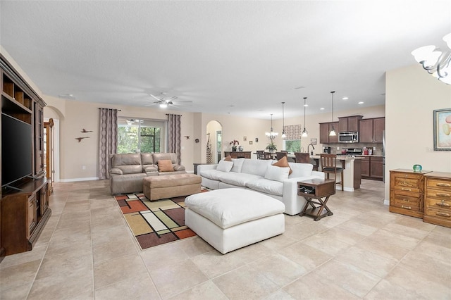 tiled living room with a textured ceiling and ceiling fan with notable chandelier