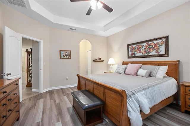 bedroom featuring a tray ceiling, light hardwood / wood-style flooring, and ceiling fan