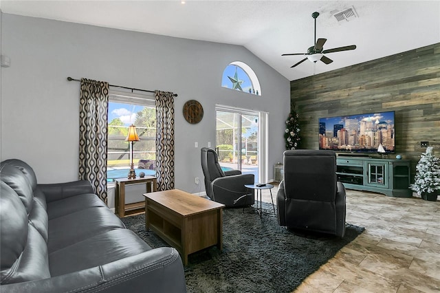 living room with high vaulted ceiling, a healthy amount of sunlight, and wood walls