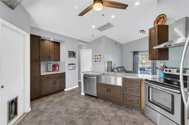 kitchen with lofted ceiling, wall chimney range hood, sink, decorative backsplash, and stainless steel appliances