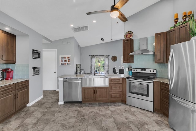 kitchen with wall chimney range hood, sink, vaulted ceiling, ceiling fan, and appliances with stainless steel finishes