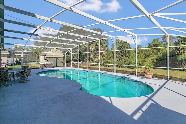 view of swimming pool with a patio area, glass enclosure, and a storage unit