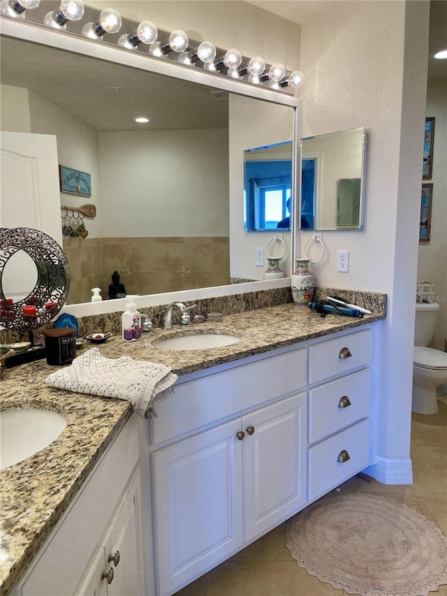 bathroom with toilet, vanity, and tile patterned floors