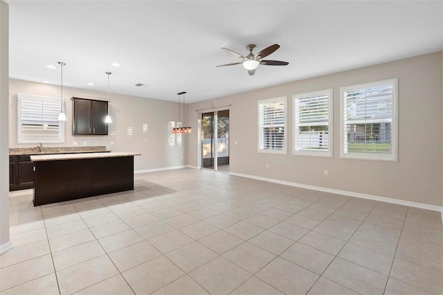 kitchen featuring dark brown cabinetry, ceiling fan, a center island, pendant lighting, and light tile patterned flooring