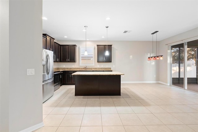 kitchen featuring a center island, sink, hanging light fixtures, stainless steel appliances, and light stone counters