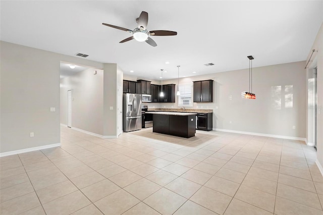 kitchen with decorative light fixtures, stainless steel appliances, a kitchen island, and ceiling fan