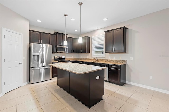 kitchen featuring a center island, appliances with stainless steel finishes, decorative light fixtures, light stone counters, and dark brown cabinets