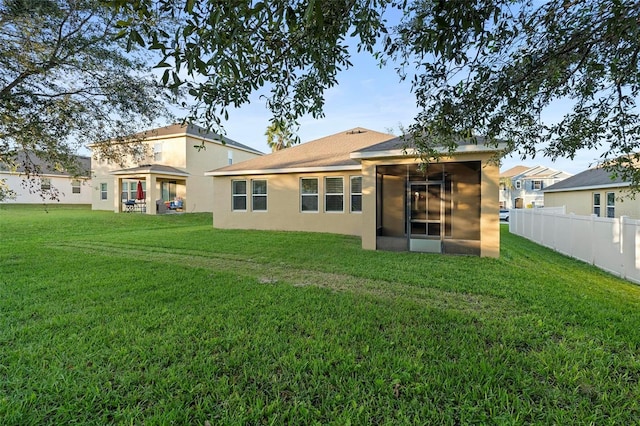 back of house with a sunroom and a lawn