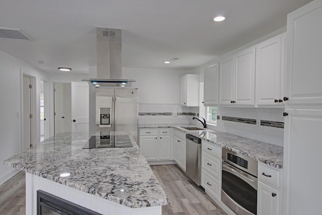 kitchen with white cabinets, light hardwood / wood-style floors, island range hood, a kitchen island, and appliances with stainless steel finishes