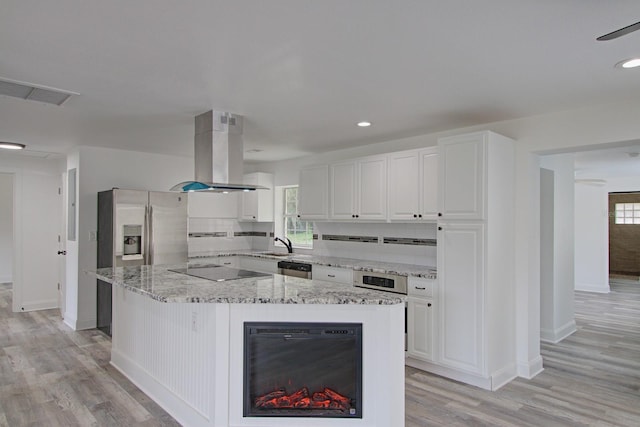 kitchen featuring white cabinetry, island range hood, a center island, and light hardwood / wood-style floors