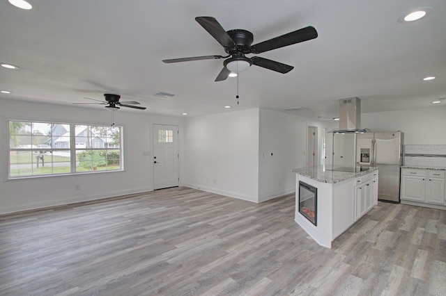 kitchen featuring island range hood, light stone counters, white cabinetry, and light hardwood / wood-style flooring