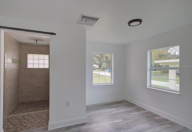 interior space with a tile shower, plenty of natural light, and hardwood / wood-style flooring