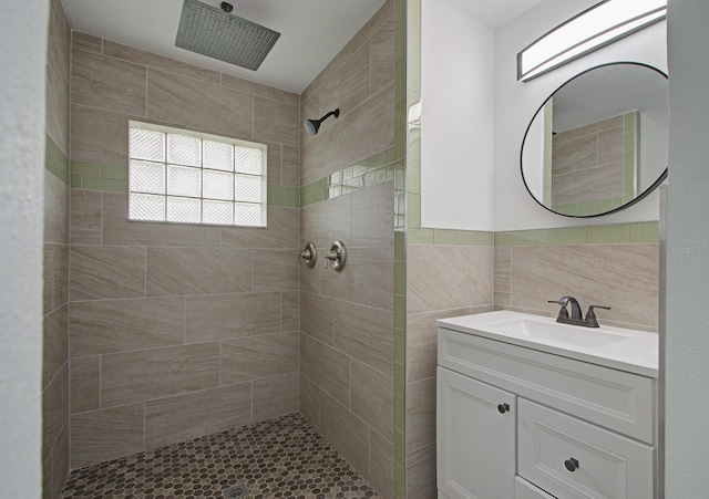 bathroom featuring tiled shower, vanity, and tile walls