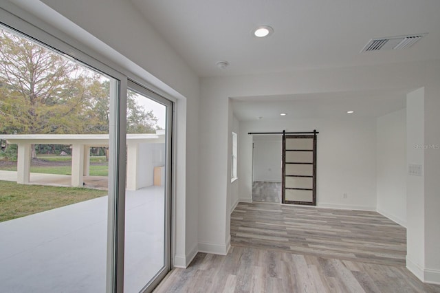 empty room with a barn door and light hardwood / wood-style floors