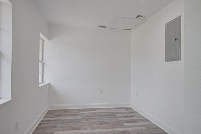 spare room featuring electric panel and light hardwood / wood-style flooring