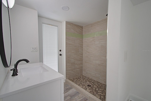 bathroom with a tile shower, hardwood / wood-style floors, and vanity