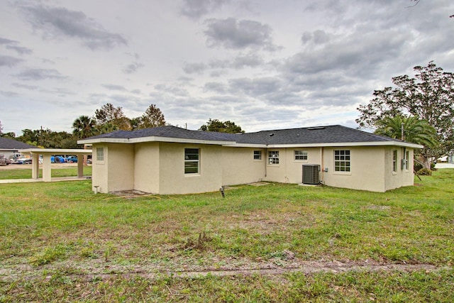 rear view of property with central AC and a yard