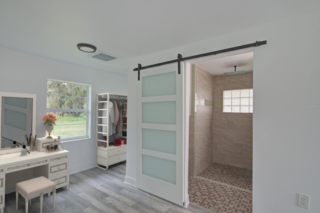 bathroom with a tile shower, wood-type flooring, and a wealth of natural light