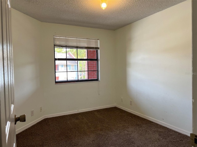 empty room with dark colored carpet and a textured ceiling