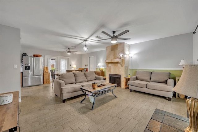 living room featuring ceiling fan, a fireplace, and light hardwood / wood-style flooring