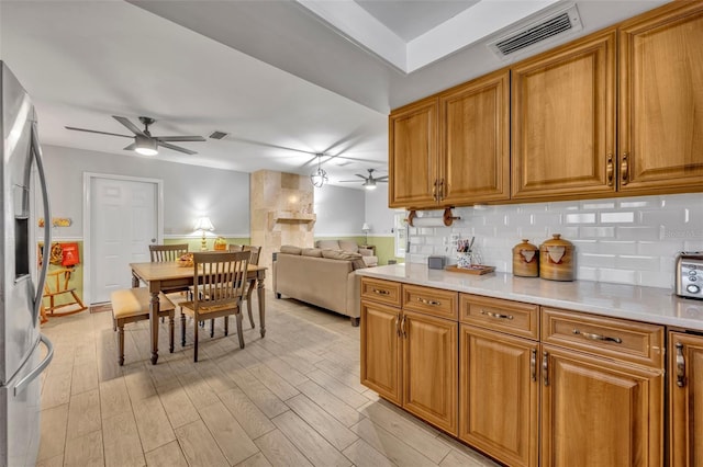 kitchen with ceiling fan, stainless steel fridge with ice dispenser, decorative backsplash, and light hardwood / wood-style flooring