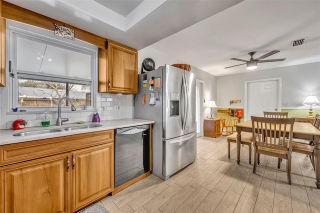 kitchen featuring sink, ceiling fan, black dishwasher, stainless steel refrigerator with ice dispenser, and tasteful backsplash