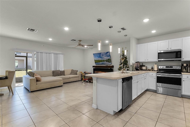 kitchen featuring kitchen peninsula, appliances with stainless steel finishes, white cabinetry, and hanging light fixtures