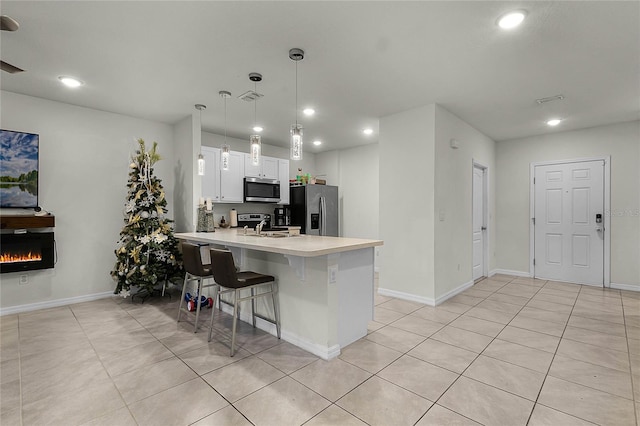 kitchen with stainless steel appliances, kitchen peninsula, decorative light fixtures, a breakfast bar, and white cabinets