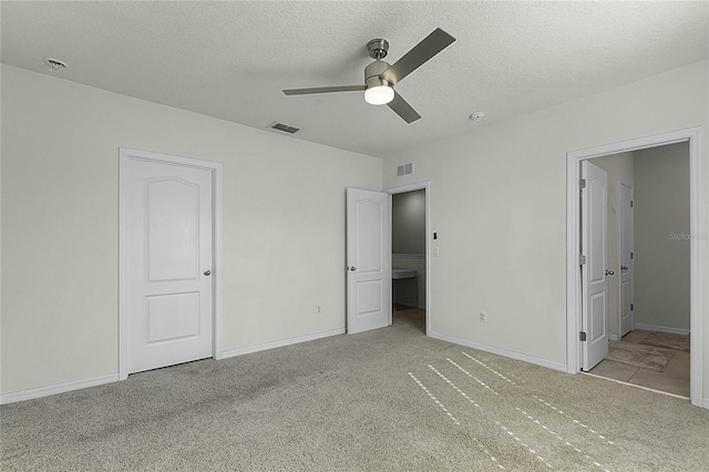 unfurnished bedroom featuring a textured ceiling, ceiling fan, light carpet, and connected bathroom