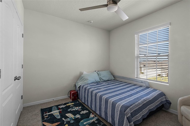 bedroom with ceiling fan, carpet floors, and a textured ceiling