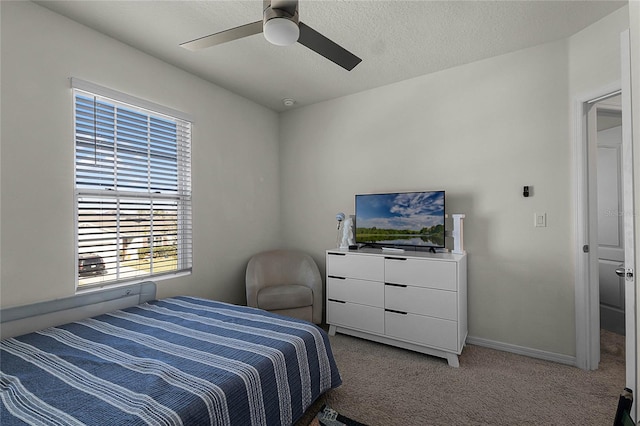 bedroom with ceiling fan, light colored carpet, and a textured ceiling