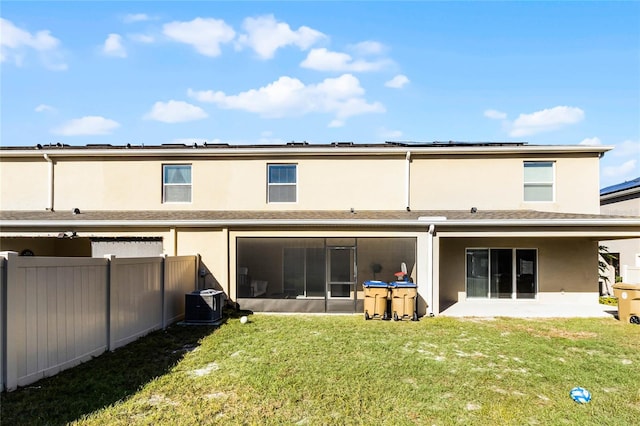 rear view of property with central AC and a lawn