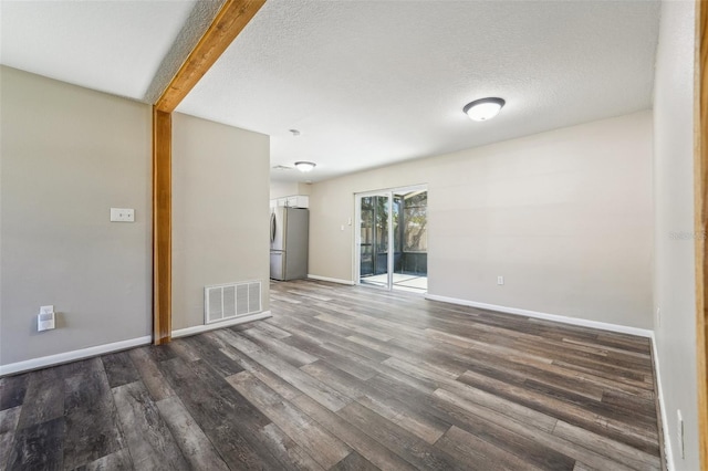 spare room featuring dark wood-type flooring and a textured ceiling