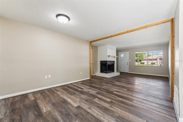 unfurnished living room featuring a textured ceiling, a fireplace, and dark hardwood / wood-style floors