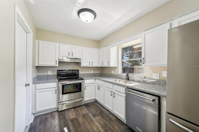 kitchen with light stone countertops, stainless steel appliances, sink, white cabinets, and dark hardwood / wood-style floors