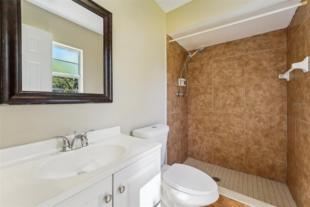 bathroom with a tile shower, vanity, and toilet