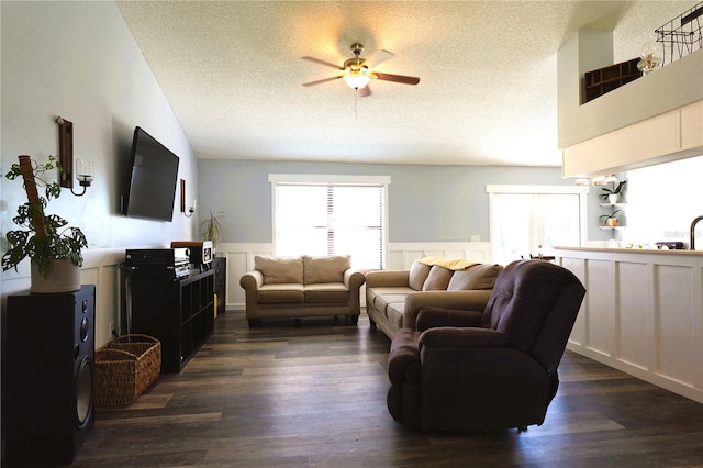 living room featuring dark hardwood / wood-style floors, ceiling fan, and a textured ceiling